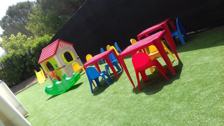 Spazio attrezzato con tavoli e sedie colorate, adatto per l'attività ludica dei bambini.