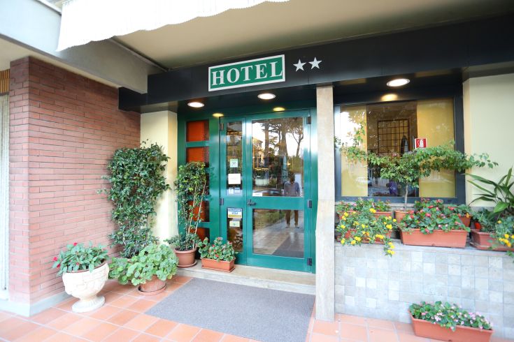 The entrance of a hotel, decorated with plants and flowers, welcomes guests in a relaxing environment.