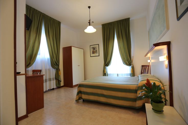 A bright room with green curtains and light wooden furniture, simple and well-organized.