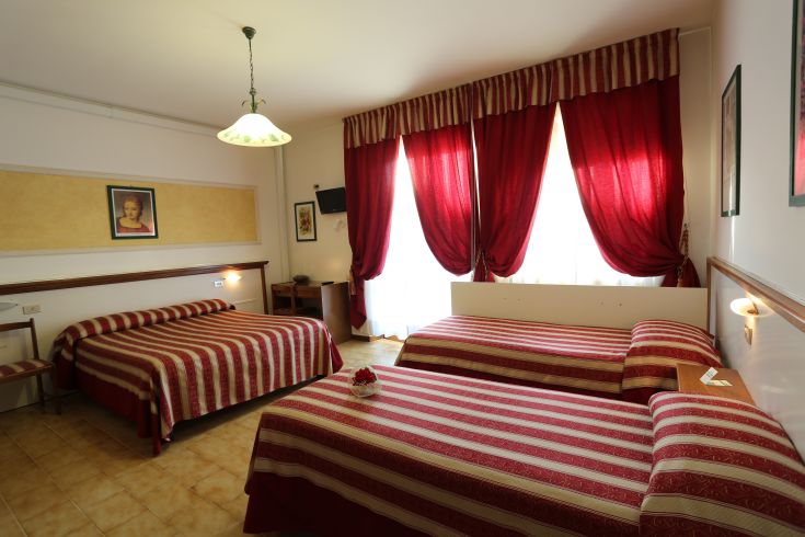 Bright and cozy bedroom with striped beds and red curtains.