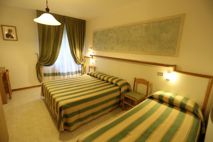 Simple bedroom with striped beds, decorated in light and bright tones.
