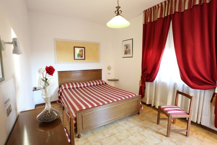 Simple room with light wooden furniture and red curtains, designed for rest and comfort.