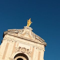The ceiling of a church featuring a golden statue under a blue sky.