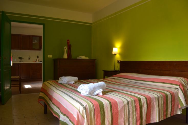 Gemütliches Wohnzimmer mit einem Doppelbett und einer gut organisierten Küche im Hintergrund.
