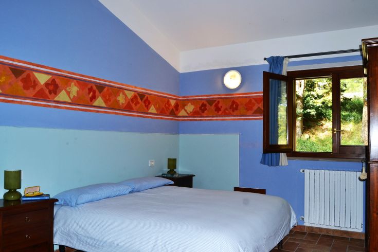 Einfache Zimmer mit blauen Farbtönen und Fenstern mit Blick auf die umliegende Landschaft.