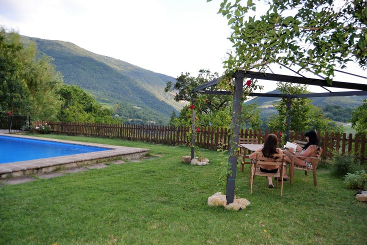 Ein ruhiger Garten mit Pool, umgeben von Bäumen und in der Ferne Bergen, perfekt für Freizeitmomente.