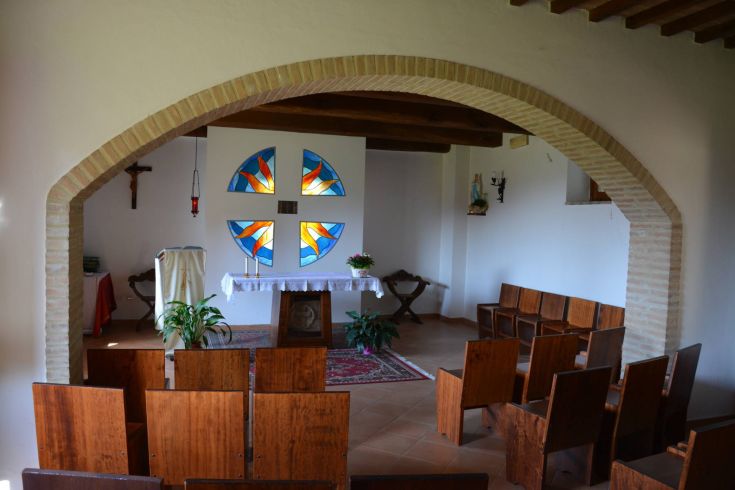 Eine einfache Kapelle mit bunten Glasfenstern und Holzbänken, ideal für Momente der Besinnung und spirituelle Rückzüge.
