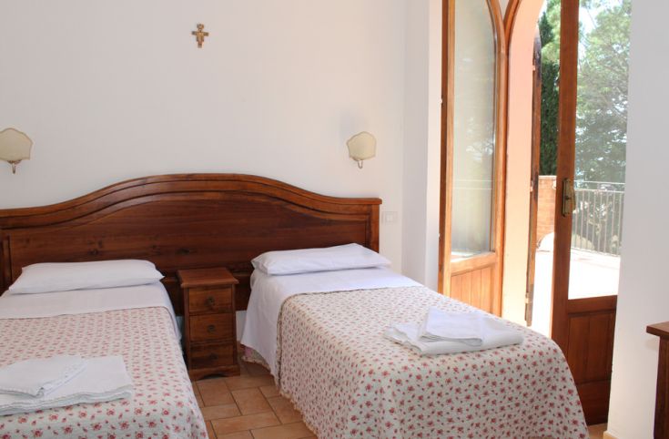 Gemütliches Zimmer mit Einzelbetten und Blick auf einen Park in einer Villa in der Nähe von Assisi.