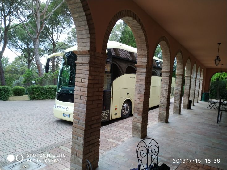 Ein Gebäude ist durch Bögen sichtbar, mit einem Bus, der auf dem Platz geparkt ist.