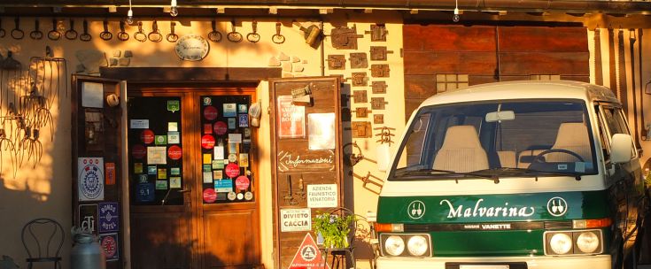 Un magasin bien aménagé avec un fourgon vintage garé devant et des enseignes colorées.