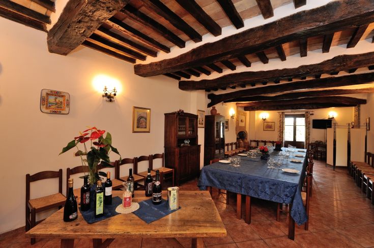 Interno di un agriturismo rustico con tavoli, bottiglie di vino e decorazioni tradizionali.
