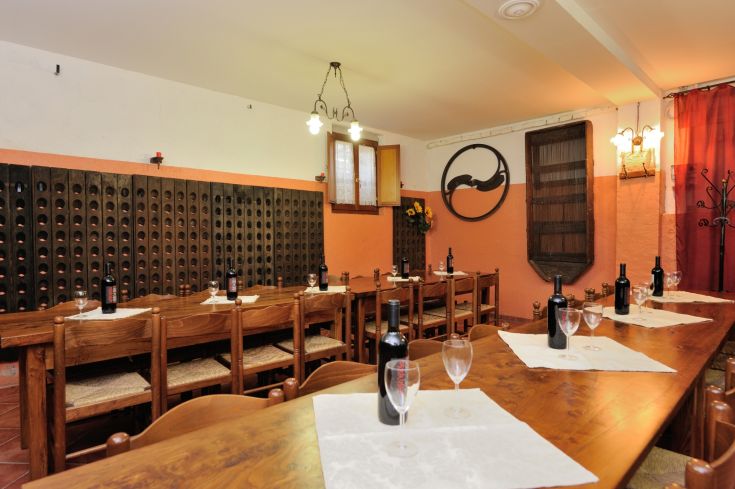 Una sala ristorante accogliente con tavoli in legno e bottiglie di vino, ideale per momenti conviviali.