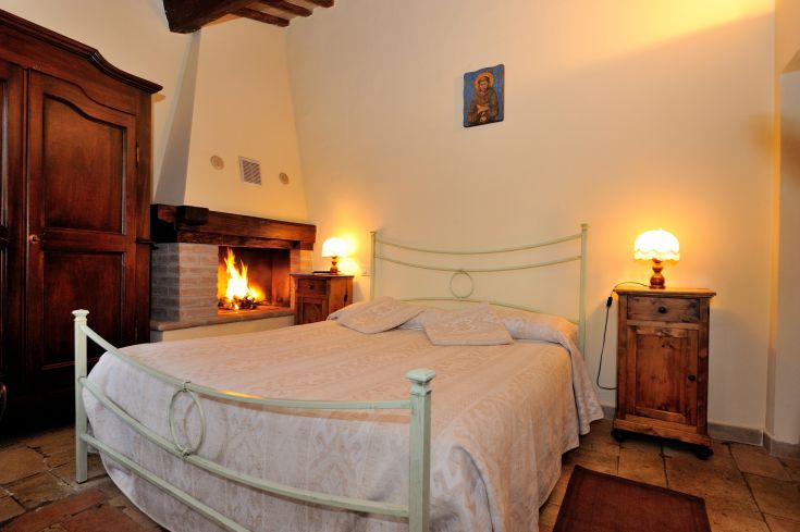 Spazio luminoso con un camino, arredato con elementi in legno e tessuti semplici, perfetto per momenti di relax.