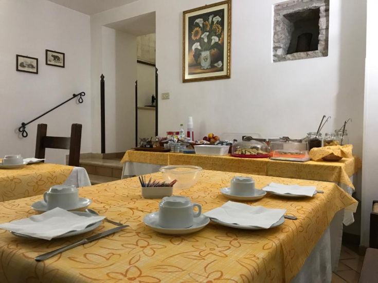 Ein einfacher Speisesaal mit angeordneten Tischen und einem Buffet mit verschiedenen Essensoptionen.