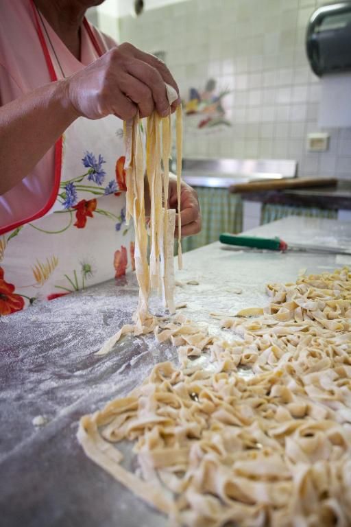 Ein Koch rollt frische Pasta auf einem Holztisch und demonstriert die italienische Kulinariktradition.