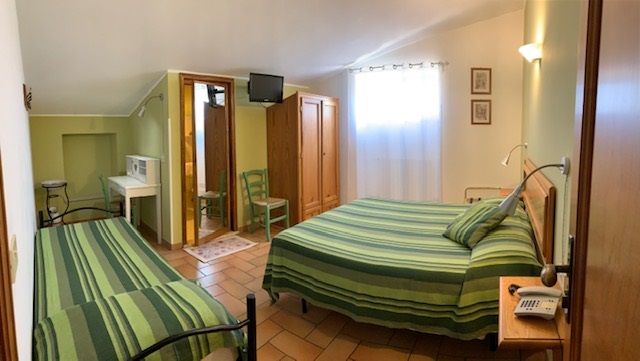 Einfaches Zimmer mit grünen gestreiften Betten, perfekt für einen ruhigen Aufenthalt.