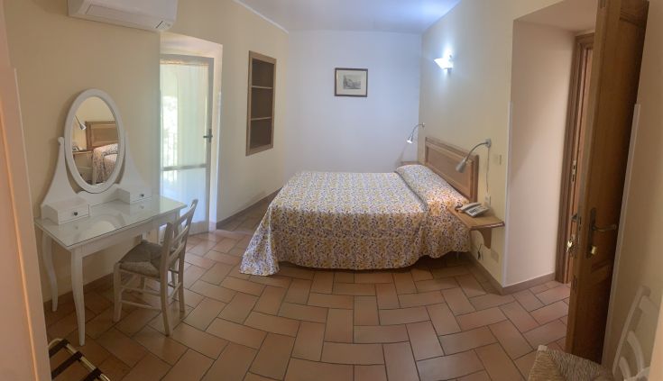 Einfaches und gemütliches Zimmer mit einem Doppelbett, Schreibtisch und natürlichem Licht. Perfekt für einen ruhigen Aufenthalt.