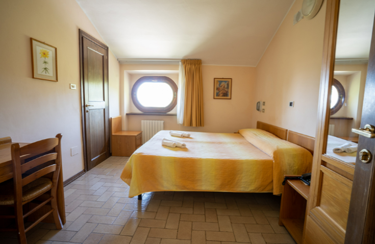Simple room with yellow beds and wooden furniture, overlooking a peaceful surrounding landscape.