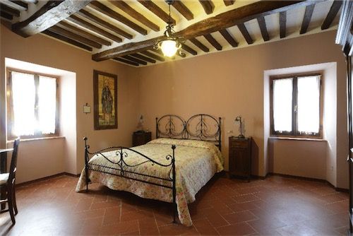 Chambre simple avec un lit en fer forgé et des détails en bois, située dans un cadre naturel.