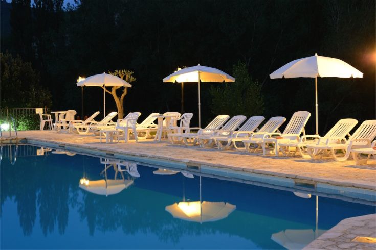Une piscine entourée de verdure, équipée de chaises longues et de parasols. Un espace paisible pour se détendre.