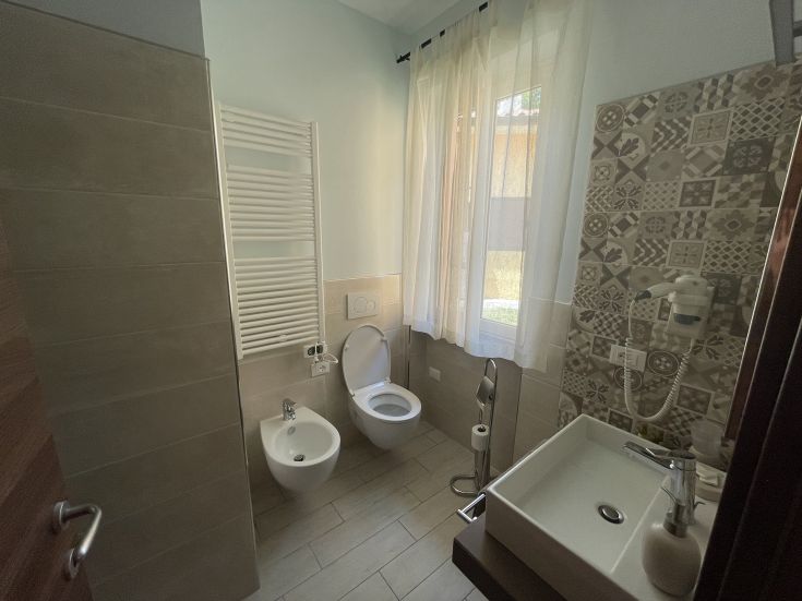 Bagno spazioso e ben illuminato, con richiami a finiture contemporanee e accessori distintivi. Atmosfera accogliente per momenti di relax.