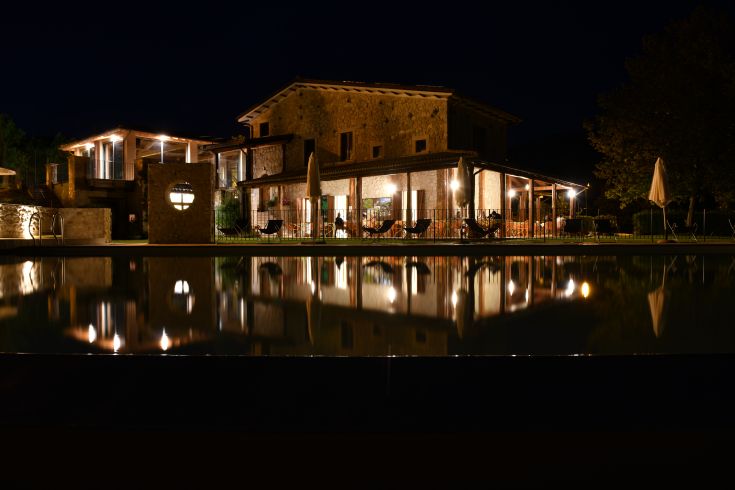 Vue nocturne du Collaccio, un agritourisme entouré de verdure, avec une piscine qui reflète la lumière.