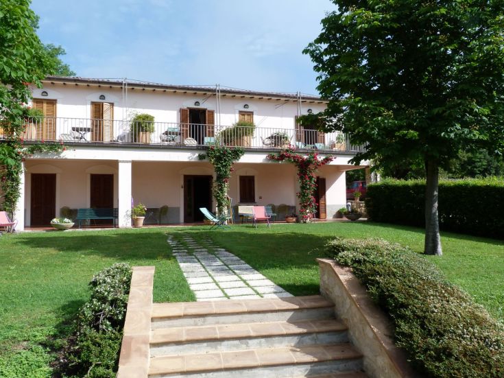 A structure surrounded by a garden, featuring a spacious terrace perfect for relaxation.