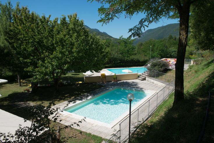 Two pools surrounded by greenery, trees, and hills, in a peaceful environment.