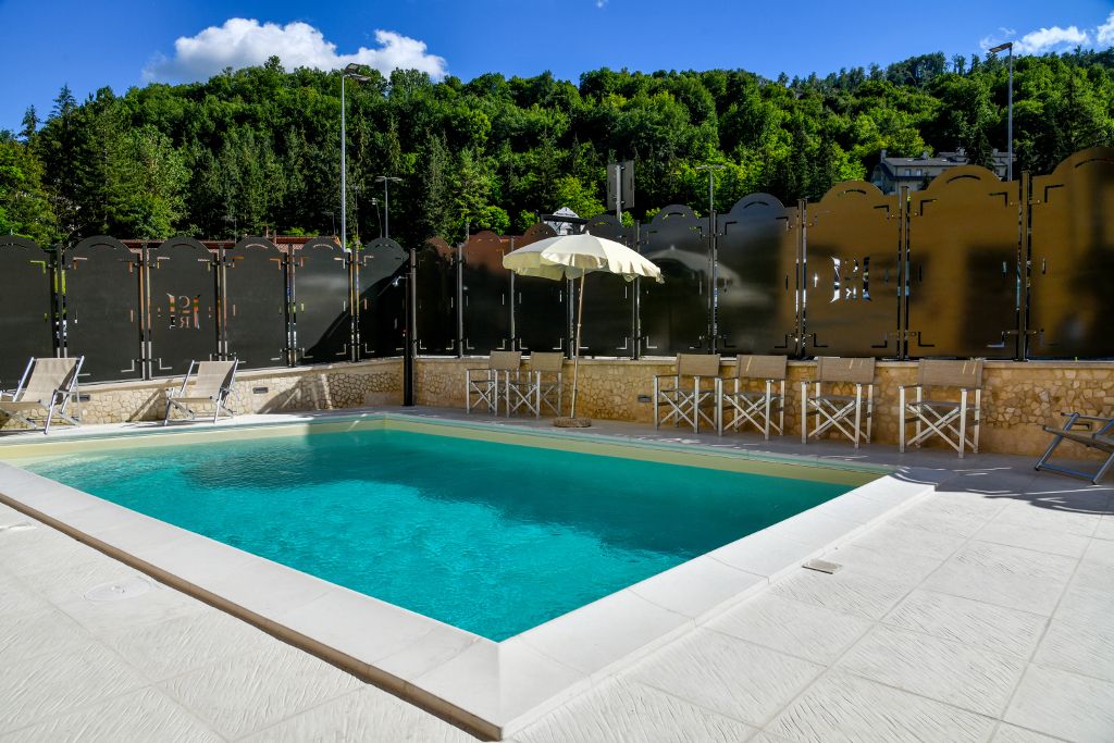 Una piscina all'aperto immersa in un ambiente naturale, circondata da verde e piante, perfetta per momenti di relax.