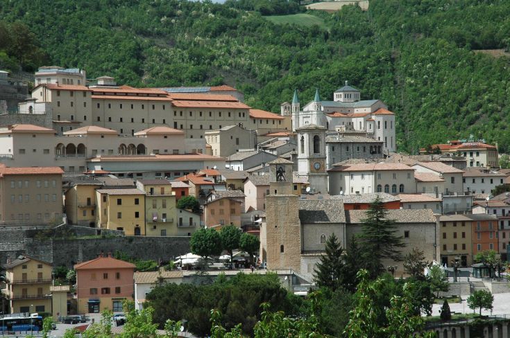 A historic village scene with old-style houses, surrounded by green hills and lush vegetation. A peaceful atmosphere.