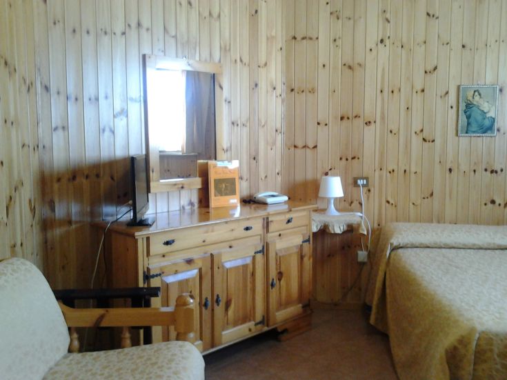 A simple wooden hotel room with rustic furnishings and basic comforts.