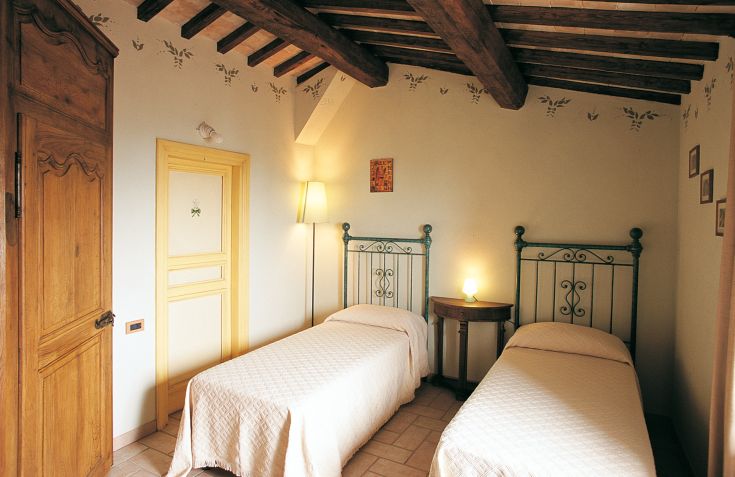 Chambre simple avec des lits simples et des éléments en bois, idéale pour un séjour paisible.