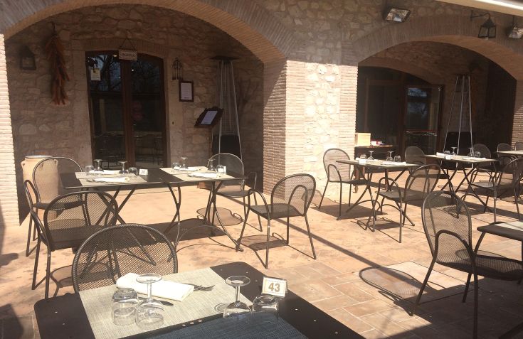 Restaurant en plein air avec des tables, offrant une ambiance calme et agréable.