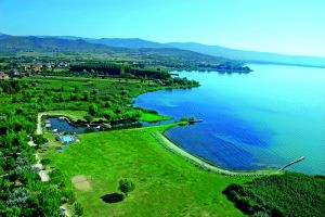 Panorama sul Lago Trasimeno, con vegetazione verde e acque calme.