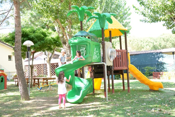 Un'area giochi vivace con bambini felici, circondata da alberi e spazi verdi.