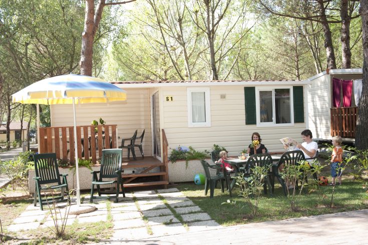 Un gruppo familiare in un contesto di campeggio, immerso nella natura, mentre trascorre momenti di tranquillità all'aperto.