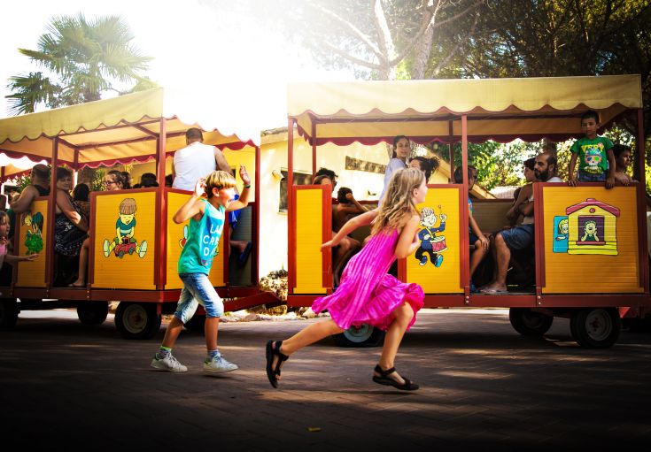 Due bambini si divertono accanto a un trenino colorato, immersi in un'atmosfera giocosa e serena.