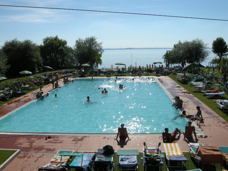 Una piscina immersa nel verde, con una scena panoramica sul lago, perfetta per momenti di relax.