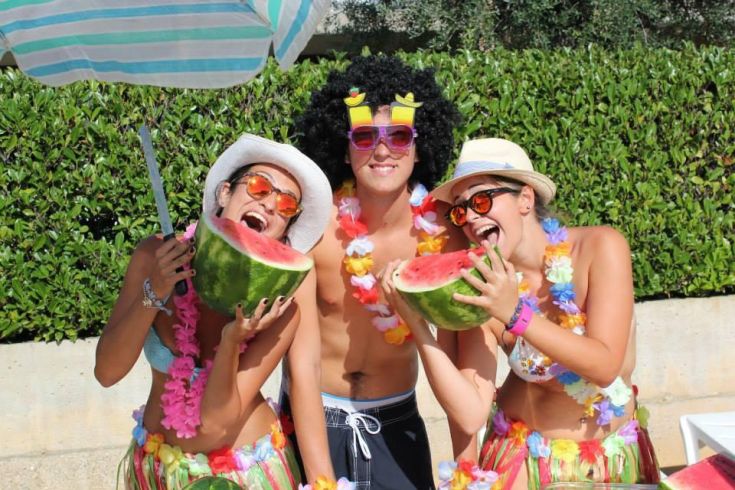 Gruppo di amici sorridenti con indumenti estivi e anguria, pronti per trascorrere una giornata all'aperto.