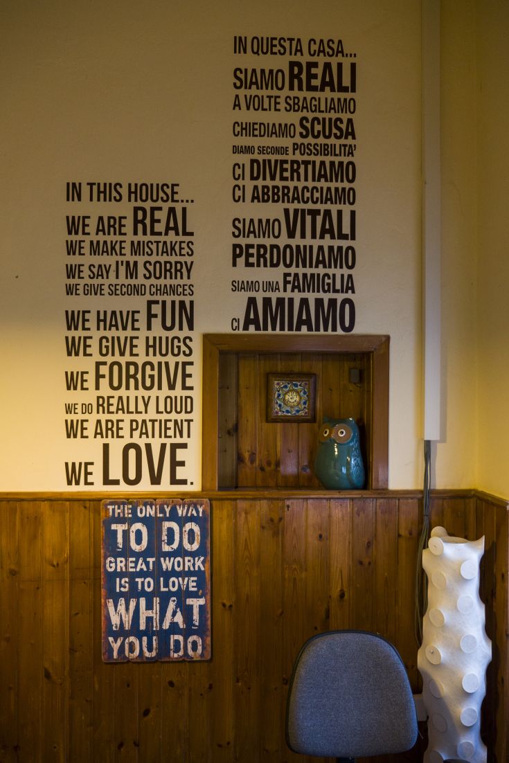 Einfache und einladende Schriftzüge an einer Wand, die familiäre und gemeinschaftliche Werte ausdrücken.