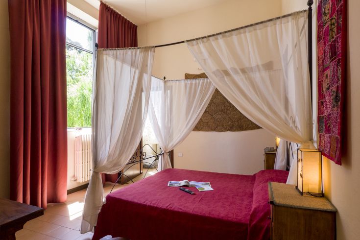 Gemütliches Zimmer mit leichten Vorhängen und einfacher Einrichtung, ideal zum Entspannen mit Blick auf den See.