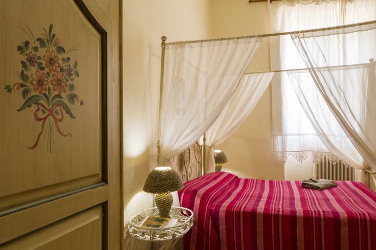 Eine einfache Kamera mit einem Himmelbett und Blumendekorationen an den Möbeln.