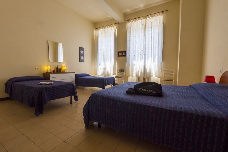 Geräumiges und gut beleuchtetes Zimmer mit Einzelbetten, ausgestattet mit schlichter und funktionaler Möbel.