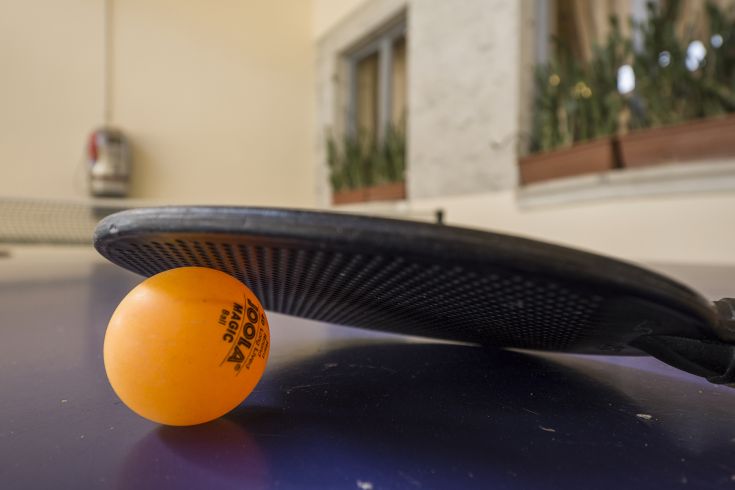 Ein Schläger und ein orangefarbener Ball auf einem Tisch für Tischtennis.