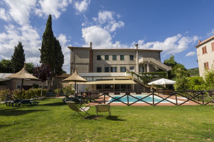 Ein Gebäude mit einem Pool, umgeben von Grün, perfekt für Momente der Entspannung im Freien.