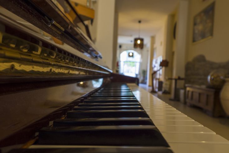 Ein Klavier in einem gut beleuchteten Flur, dessen natürliches Licht eine warme und einladende Atmosphäre schafft.