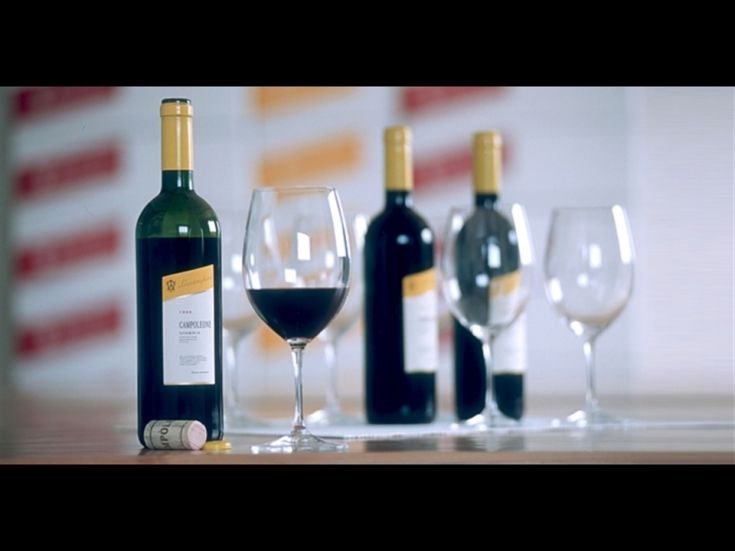 A fine wine bottle is in the foreground, accompanied by glasses arranged on a table.