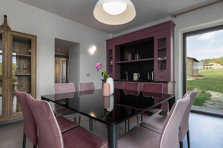 Modern space with a black table and fabric chairs, illuminated by a simple designed lamp.
