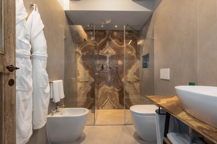 A modern bathroom featuring a glass shower and stone details. Simple and refined atmosphere.