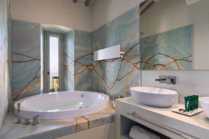 A simple bathroom featuring a circular tub and blue marble walls, designed for relaxation.